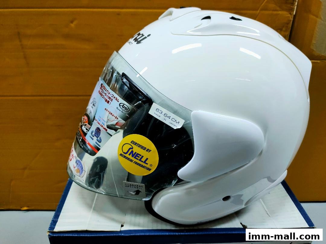 A white Arai motorcycle helmet with a clear visor and various stickers.