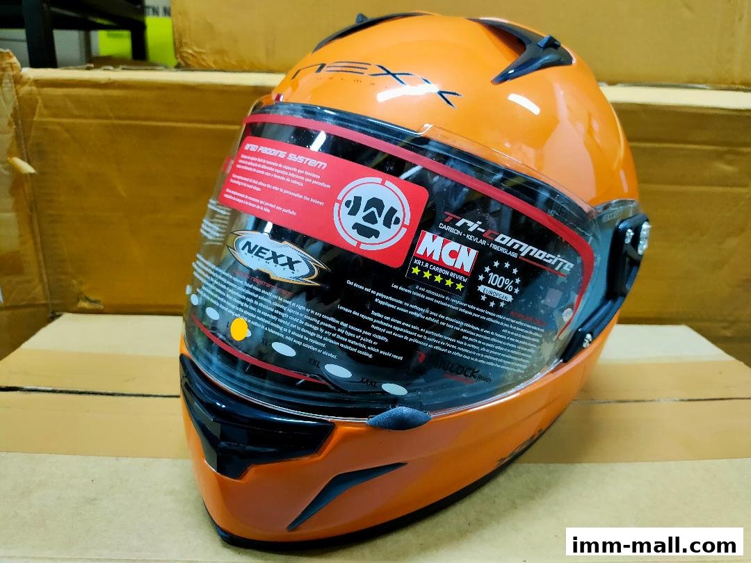 An orange Nexx motorcycle helmet with a clear visor and detailed product information stickers.