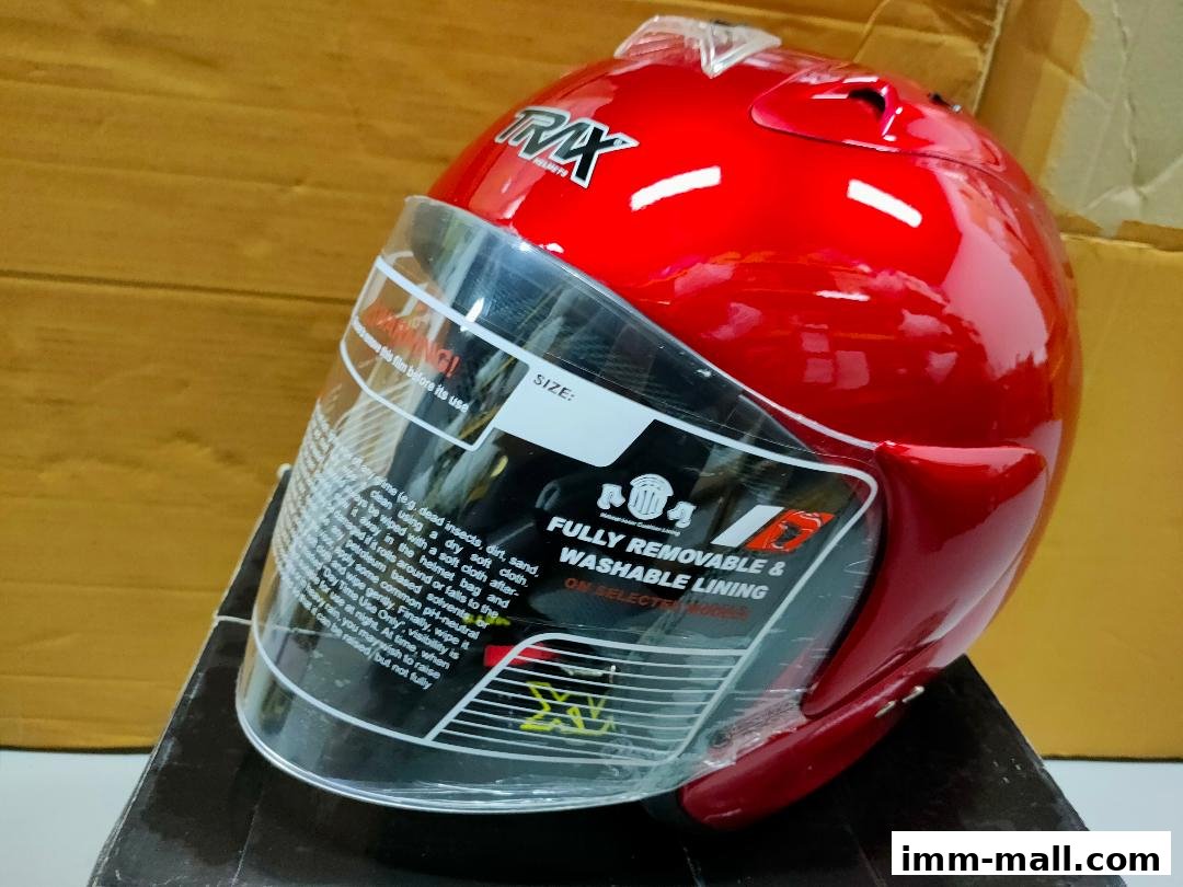 A shiny red motorcycle helmet with a clear visor and detailed care instructions.