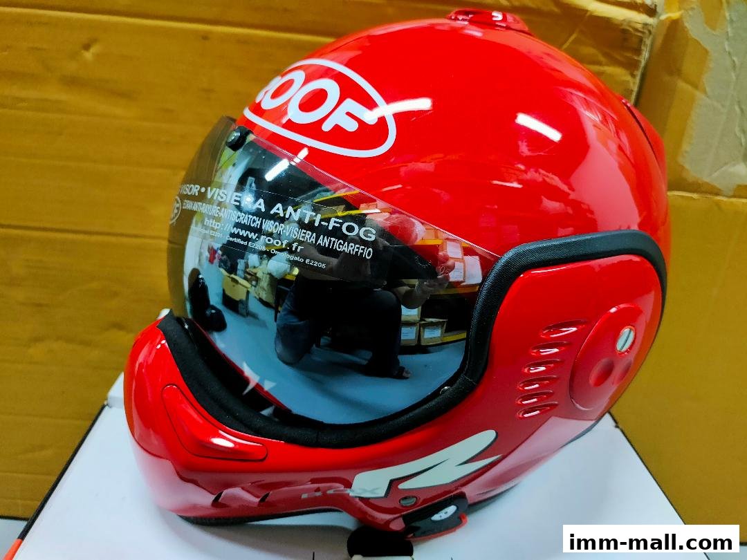 A bright red motorcycle helmet with a clear visor and the brand logo visible.