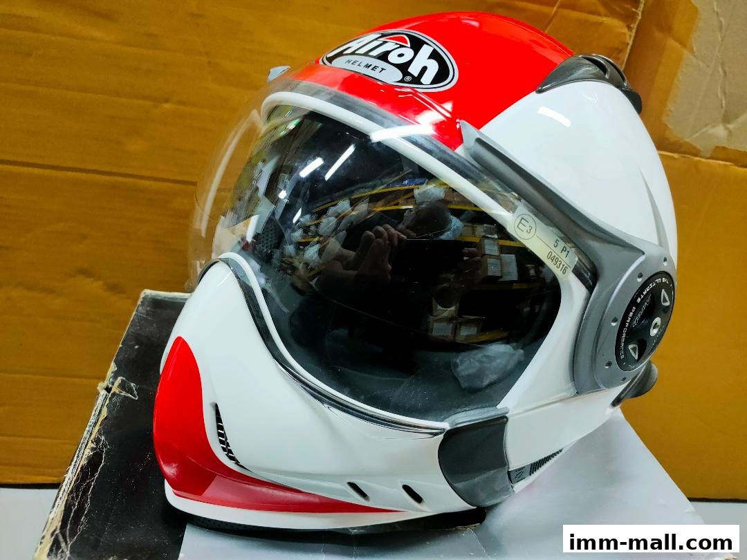 A red and white Airoh motorcycle helmet with a clear visor is displayed.