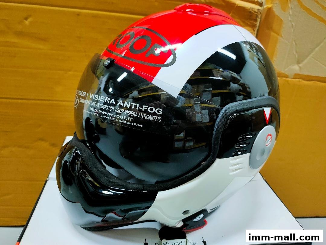 A close-up of a red, white, and black motorcycle helmet with an anti-fog visor.