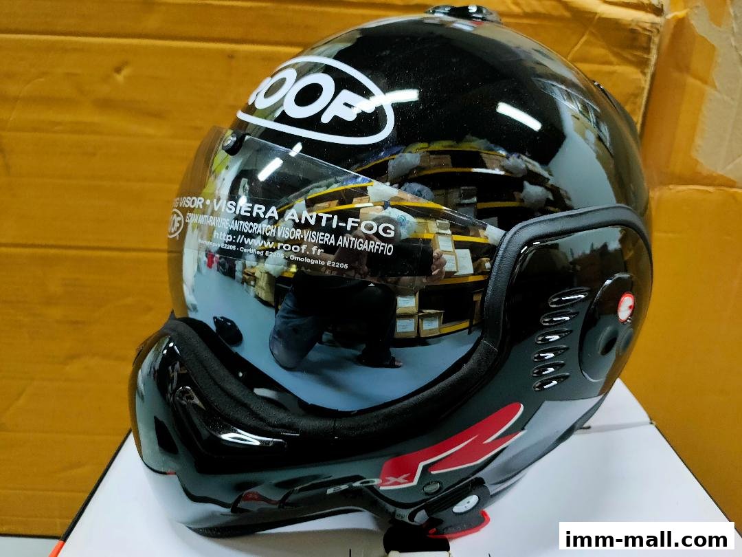 A black motorcycle helmet with a clear visor, reflecting shelves of products.