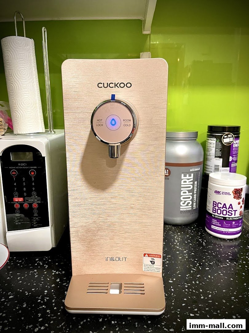 A Cuckoo water dispenser is shown with supplements and a microwave in the background.