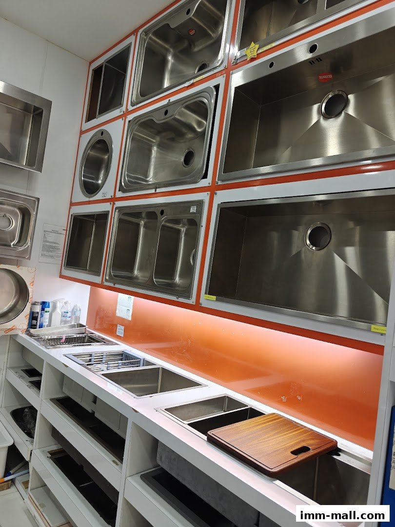 A display of various stainless steel kitchen sinks and accessories.