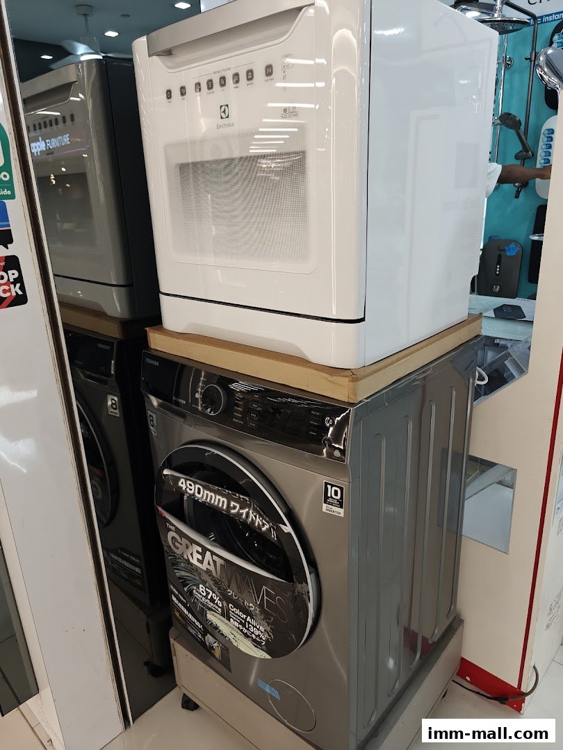 A white Electrolux dishwasher sits atop a silver Toshiba washing machine.