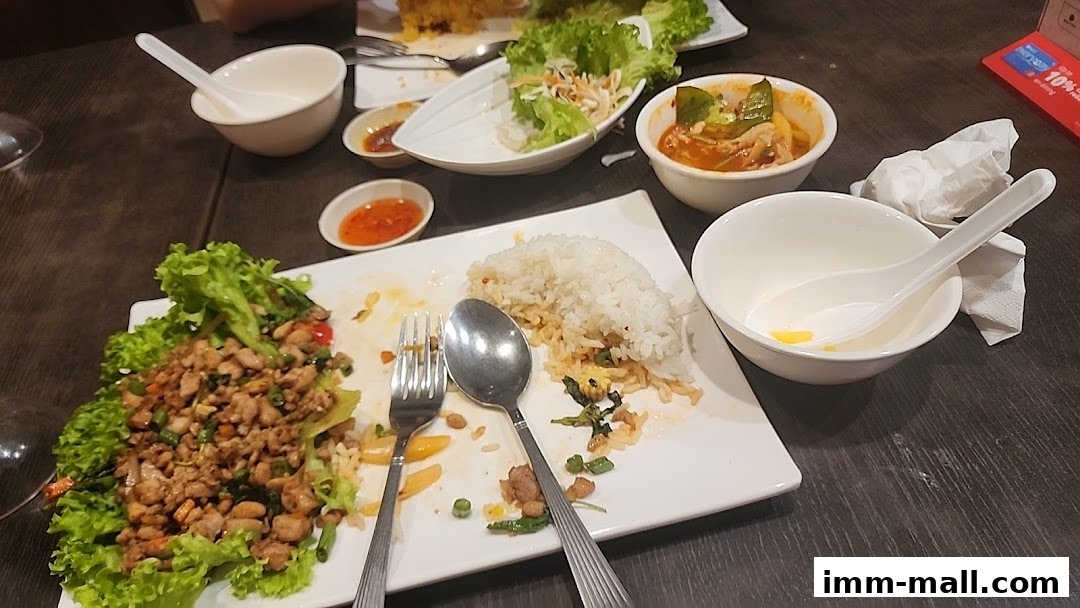A table with partially eaten Thai food, including rice, meat, and soup.