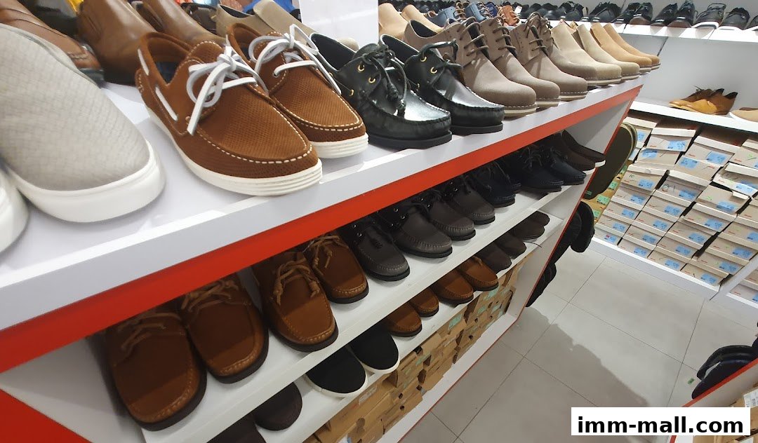 A wide selection of men's shoes displayed on shelves, with shoe boxes stacked in the background.