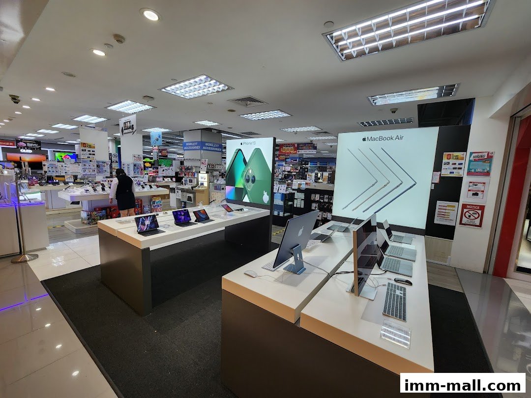 Interior view of an electronics store showcasing Apple products like MacBooks and iPhones.