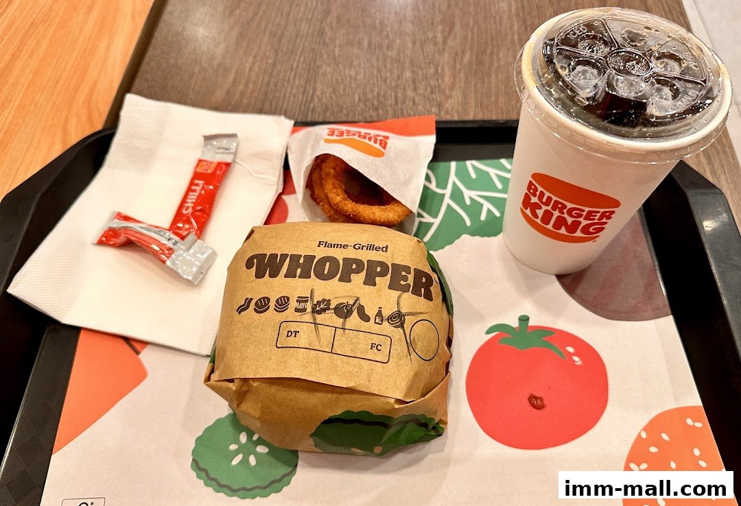 A Burger King Whopper meal with onion rings and a drink on a tray.