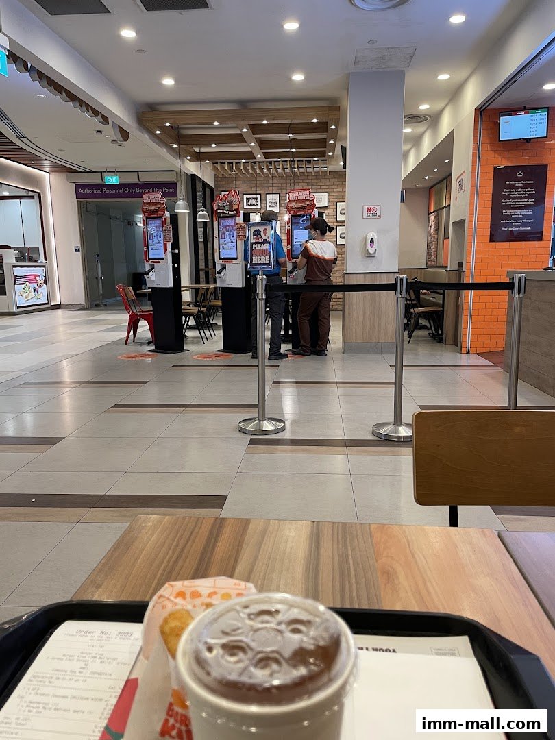 Burger King interior with customers ordering at kiosks and a tray with food and drink.