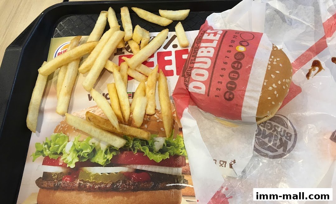 A Burger King meal with fries and a burger on a tray with promotional material.