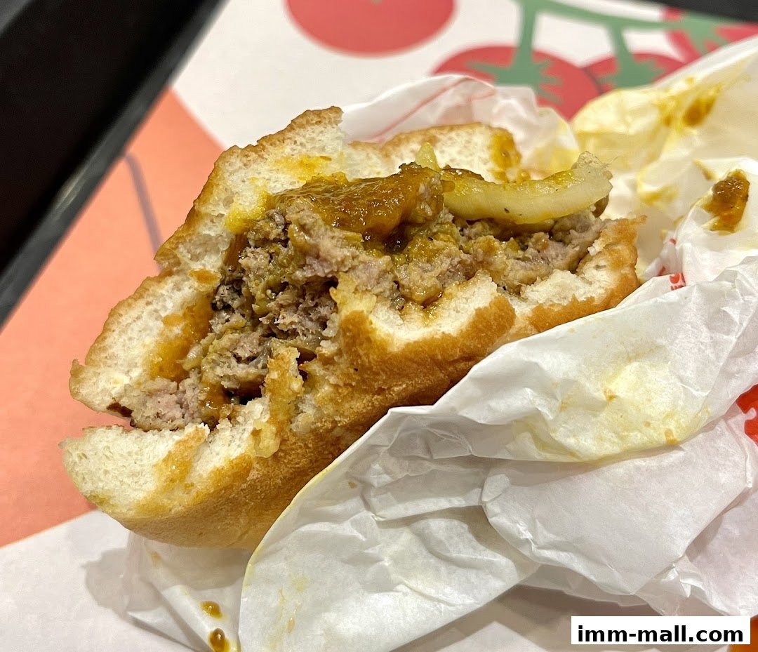 A close-up of a partially eaten burger with a thick patty and sauce.