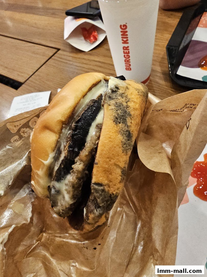 A close-up of a Burger King Whopper burger with a drink and ketchup packets.