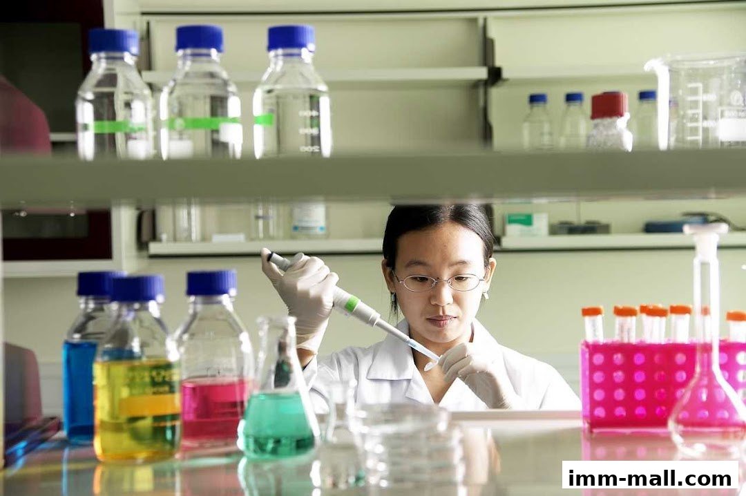 A scientist in a lab coat uses a pipette with colorful liquids in beakers and test tubes.