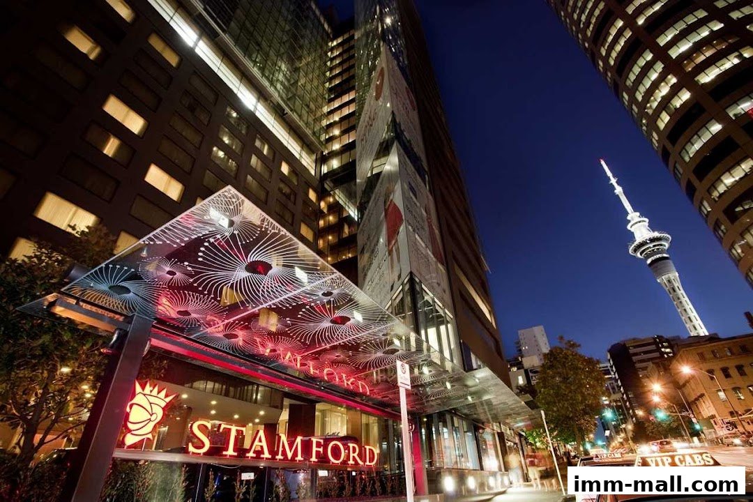 The illuminated entrance of the Stamford hotel at night with a prominent sign and city skyline.