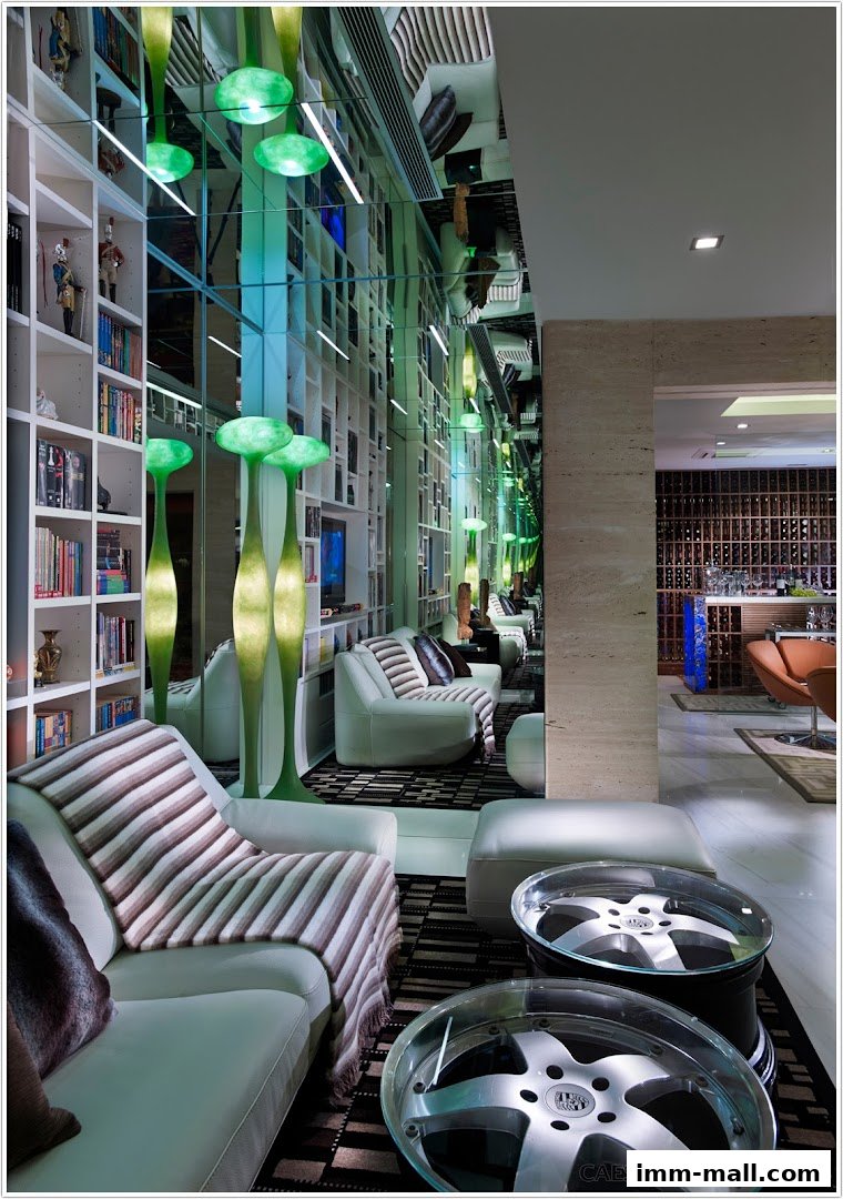 Modern lounge area with white sofas, bookshelves, and unique green floor lamps.