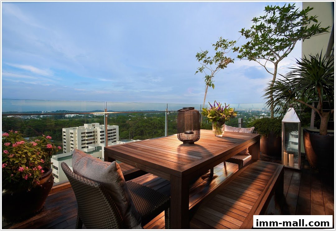 A wooden dining set on a balcony with a scenic city view at dusk.