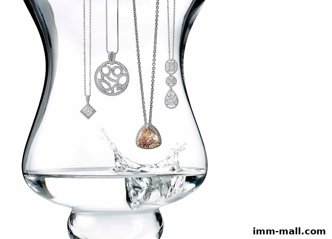 A collection of exquisite diamond and gemstone necklaces displayed inside a glass vase with water.