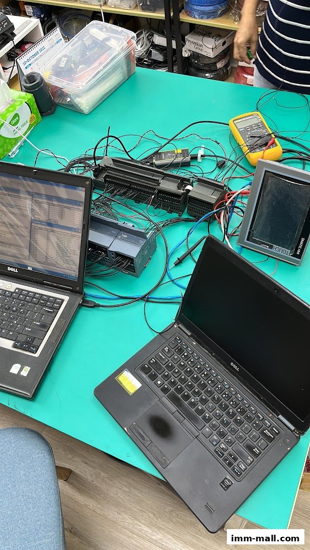 Two laptops and electronic components are set up on a teal desk for testing and development.