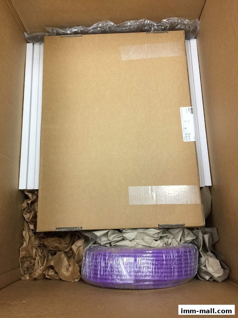 A cardboard box containing packaged items, including a large flat cardboard and a coiled purple item.