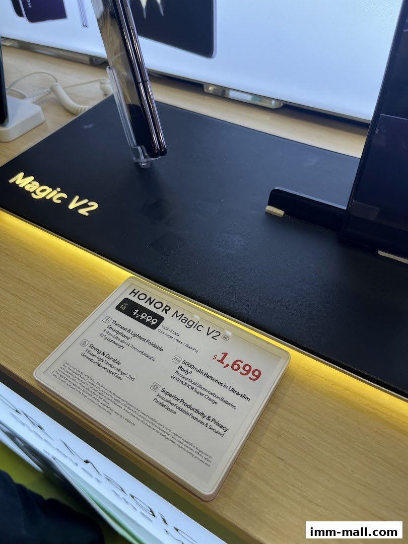 A display stand showcasing the HONOR Magic V2 foldable smartphone with pricing information.