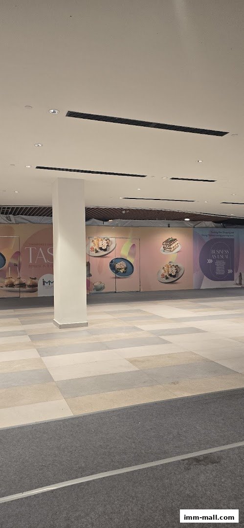 A shopping mall interior with a pillar and large posters advertising food.