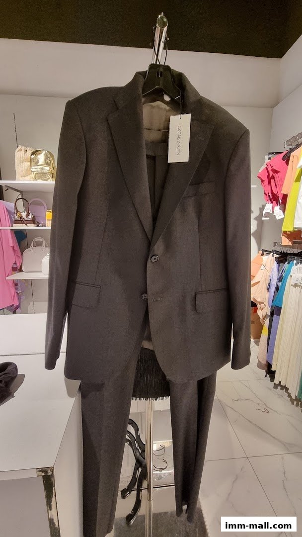 A dark grey Calvin Klein suit is displayed on a hanger in a retail store.