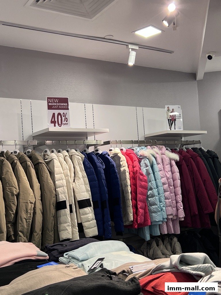 A display of colorful puffer jackets and folded sweaters in a retail store.