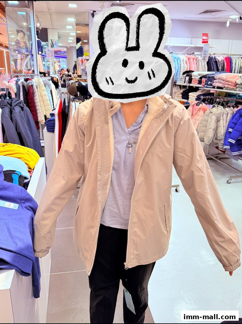 A person wearing a beige jacket and black pants stands in a clothing store.