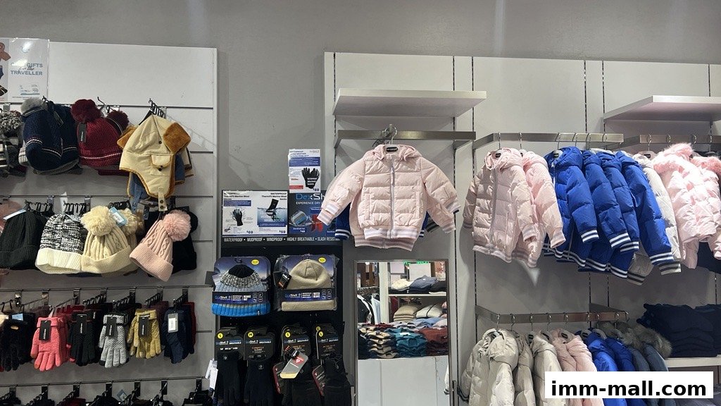 A retail display featuring winter clothing, including puffer jackets, hats, and gloves.