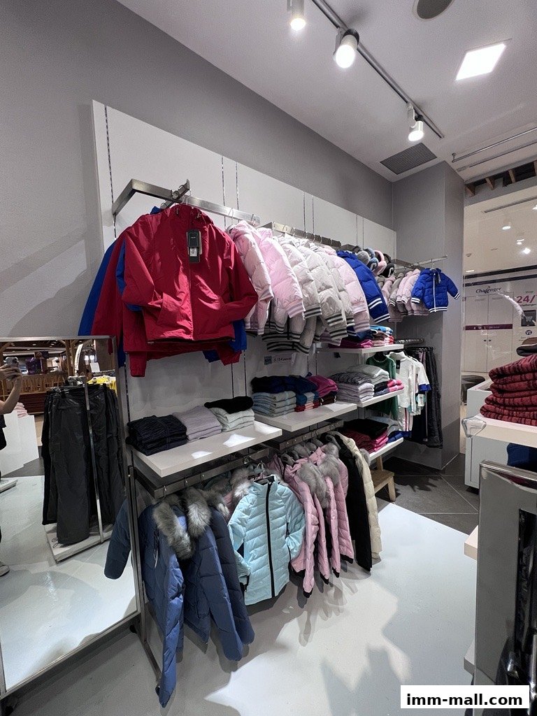 A retail shop interior displaying various winter jackets and folded clothing on shelves.