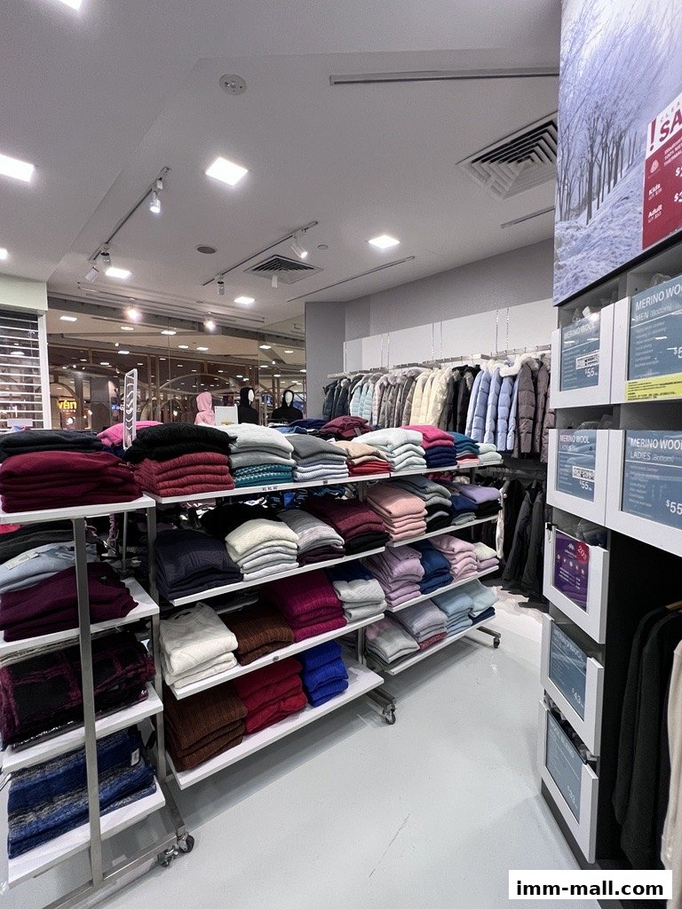 Interior view of a COLDWEAR IMM Outlet store showcasing folded sweaters and hanging jackets.