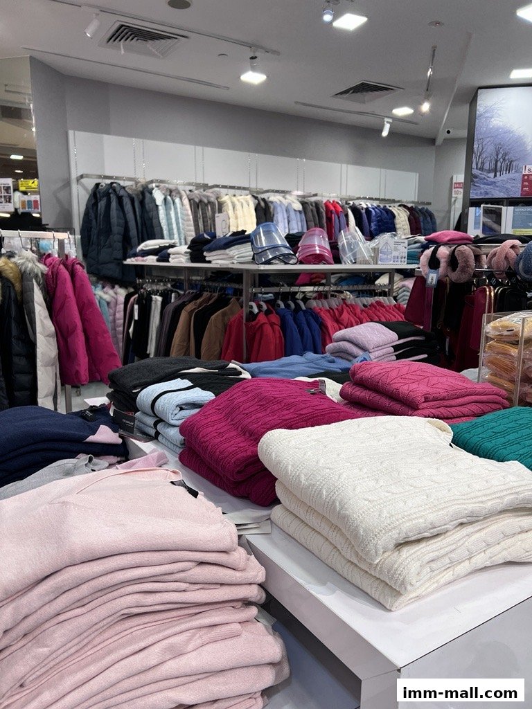 A retail store interior displaying stacks of folded sweaters and racks of outerwear.