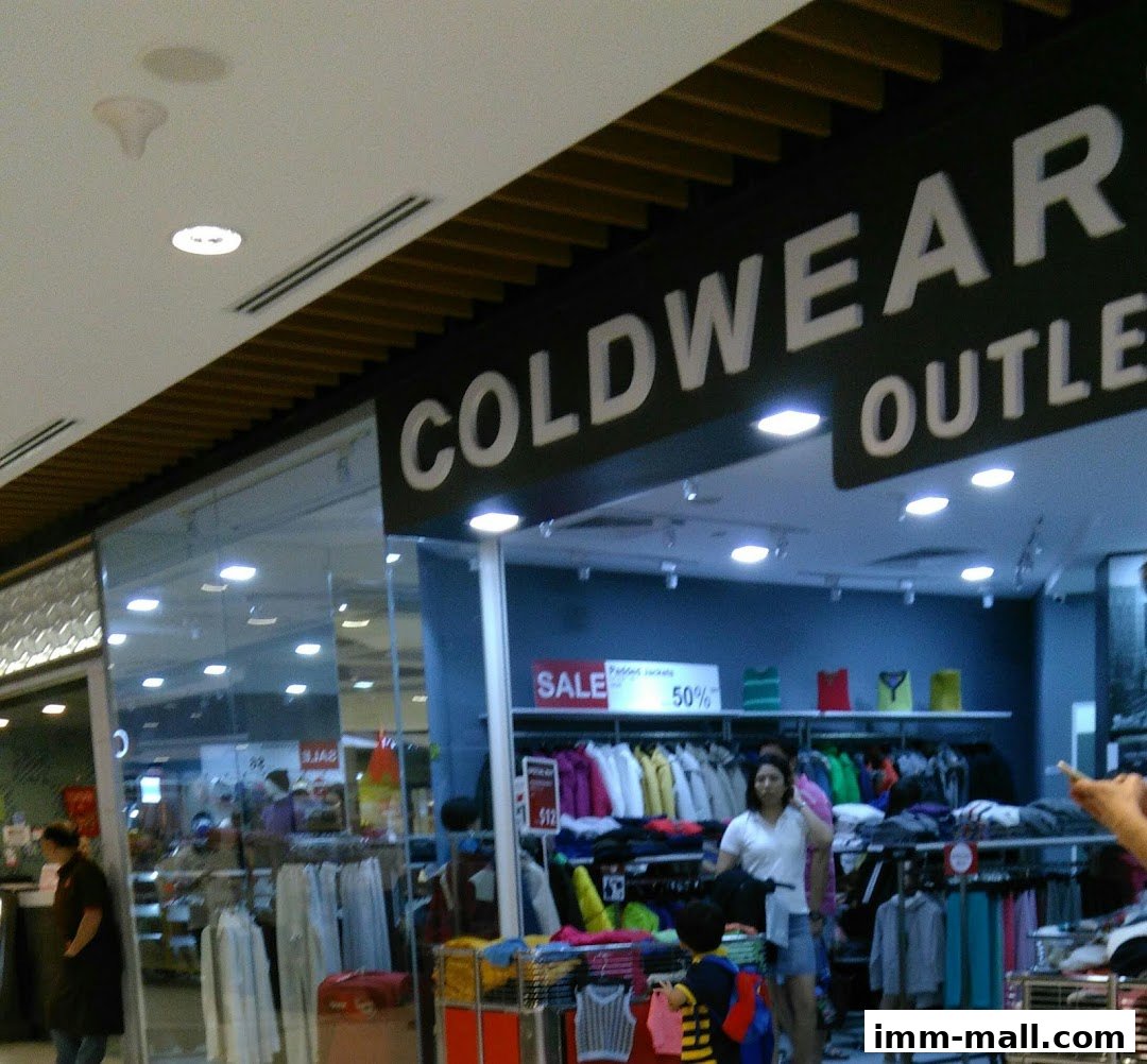 The entrance of a COLDWEAR IMM Outlet store with clothing displays and sale signs.