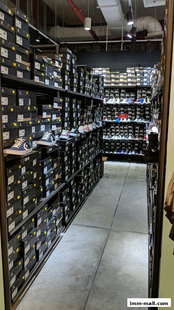 A wide aisle in a Converse store filled with shelves of shoe boxes and displayed sneakers.