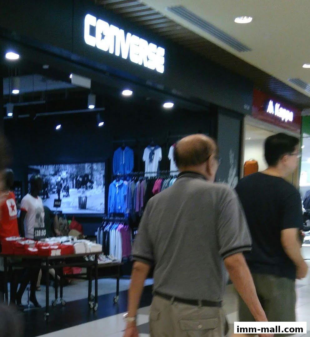 The Converse IMM shop front with clothing displayed and people walking by.