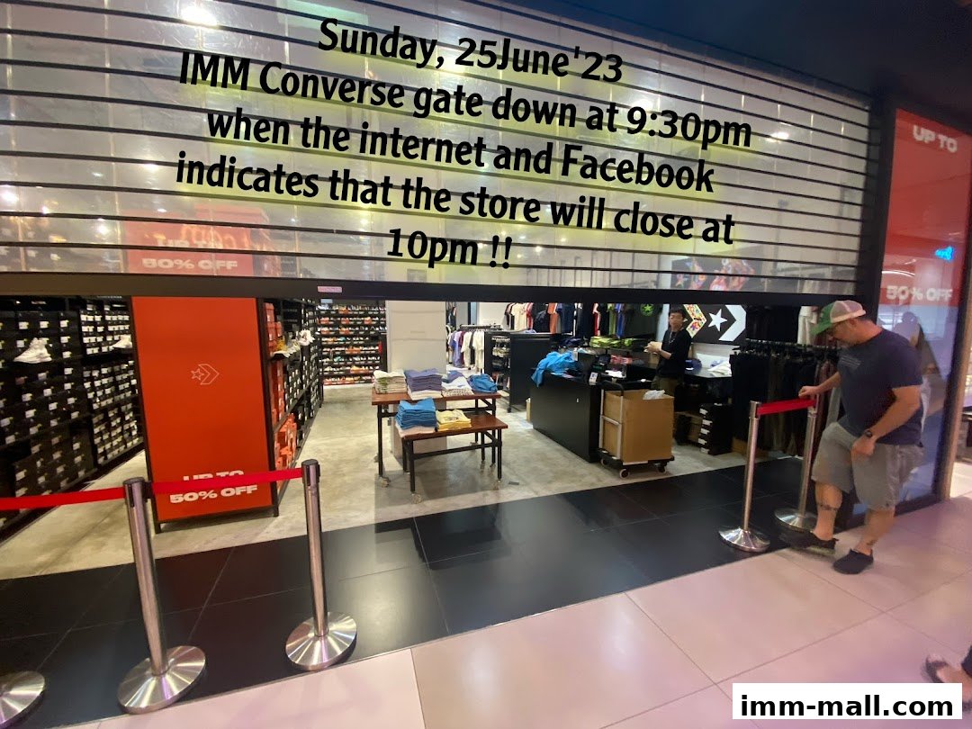 The Converse IMM store with its gate partially down, showing merchandise and staff inside.