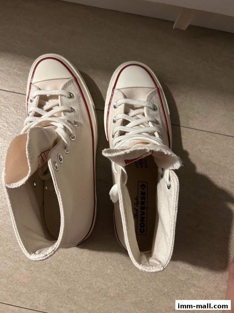 A pair of classic white high-top Converse sneakers with red trim.