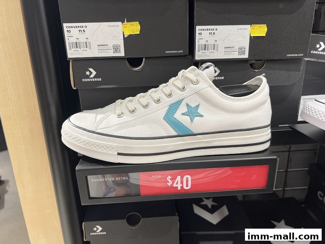 A white Converse sneaker with a blue star logo is displayed on a shelf with boxes.