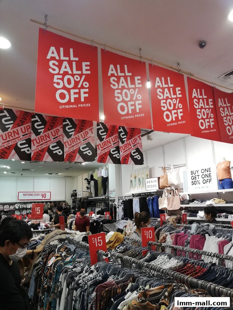 A clothing store interior with sale signs and racks of clothes.