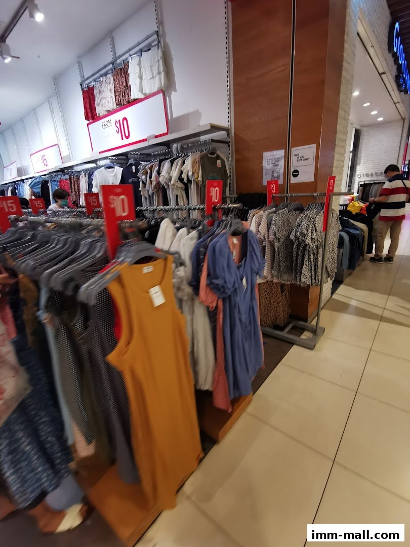 Interior view of a clothing store with racks of apparel and sale signs.