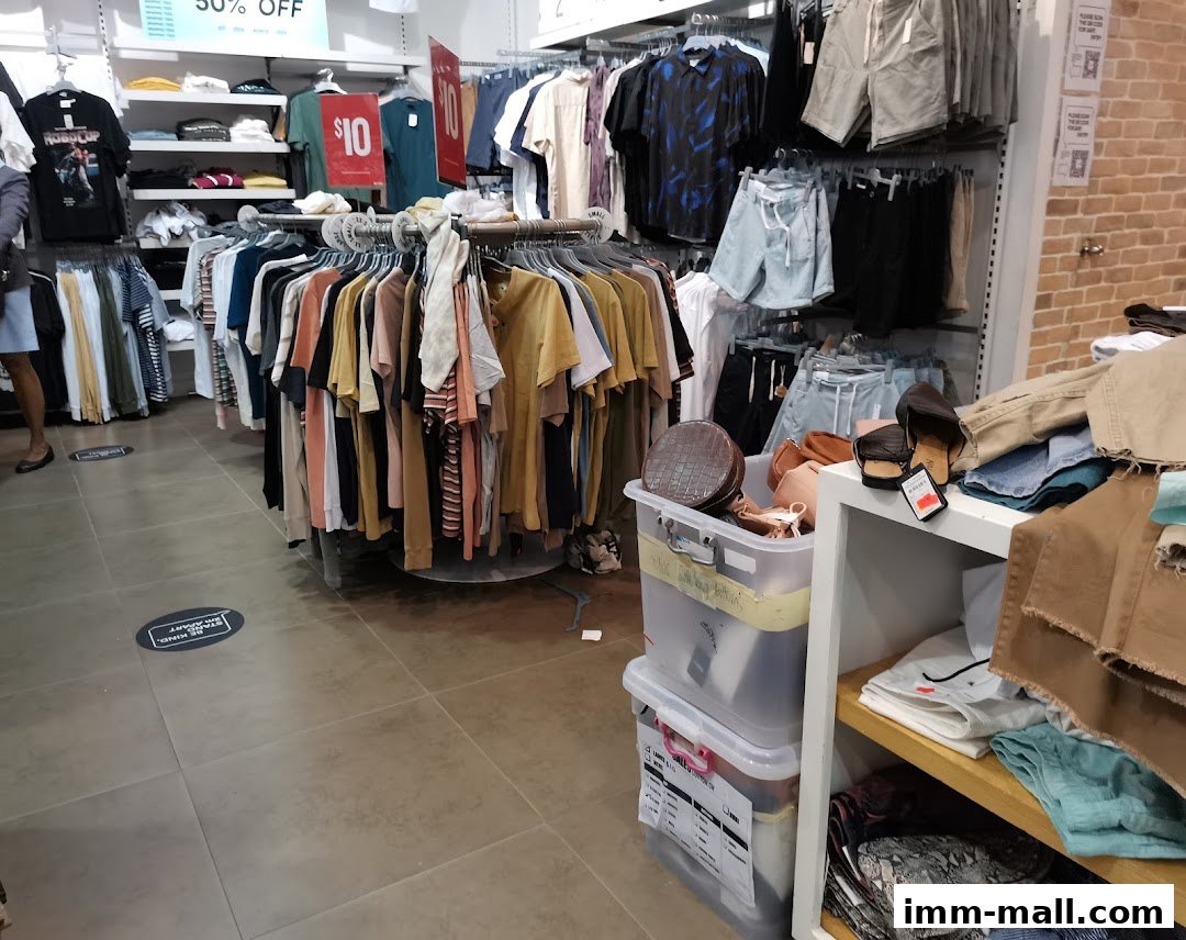 Interior view of a clothing store with racks of apparel and sale signs.