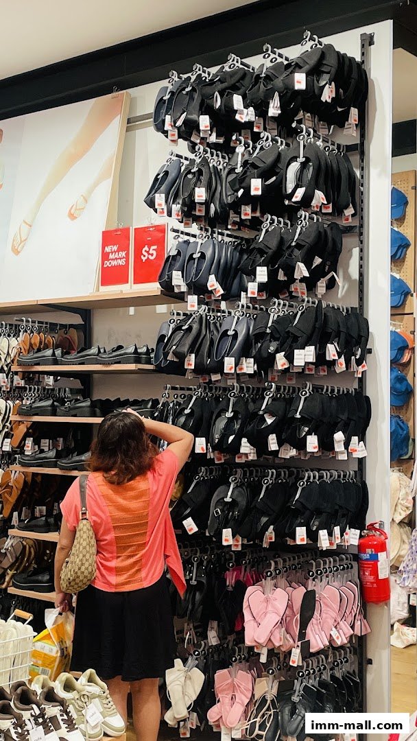 A shopper browses a wide selection of shoes, including flats, sandals, and sneakers, at Cotton On.