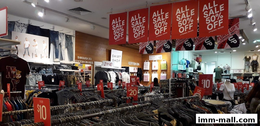 Interior view of a Cotton On store with racks of clothing and sale signs.