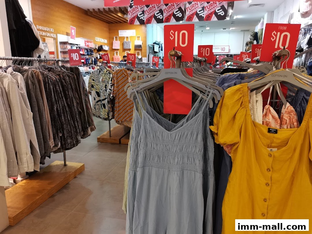 Interior view of a Cotton On store with racks of clothing and sale signs.