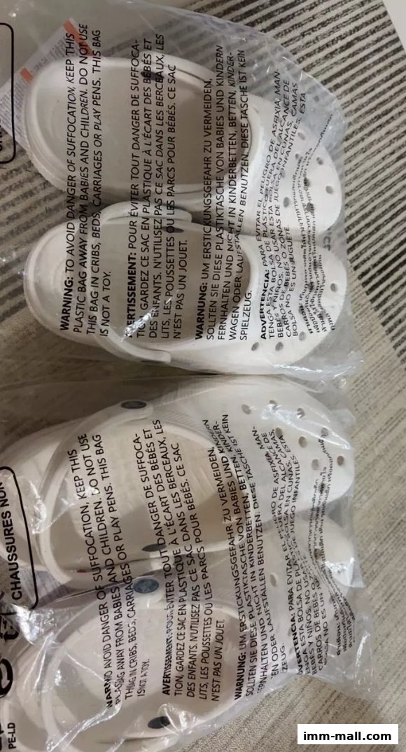 Several pairs of white Crocs shoes are packaged in clear plastic bags with warning labels.