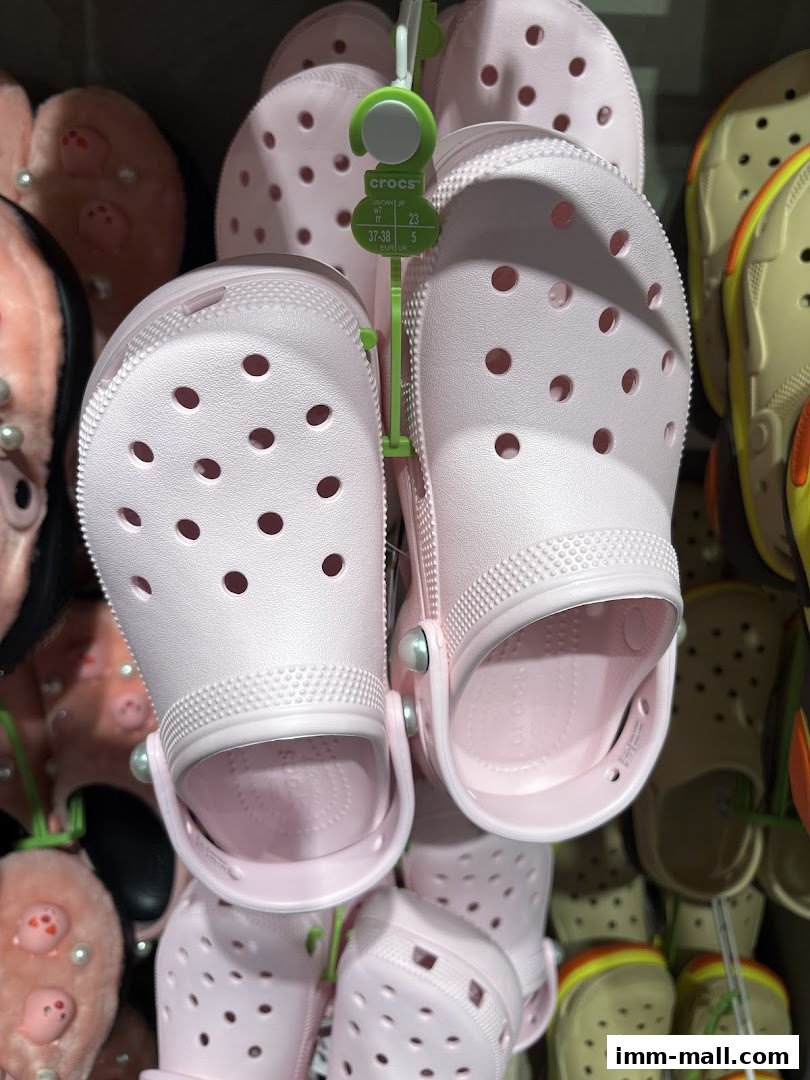 A close-up view of several pairs of light pink Crocs shoes hanging on display.