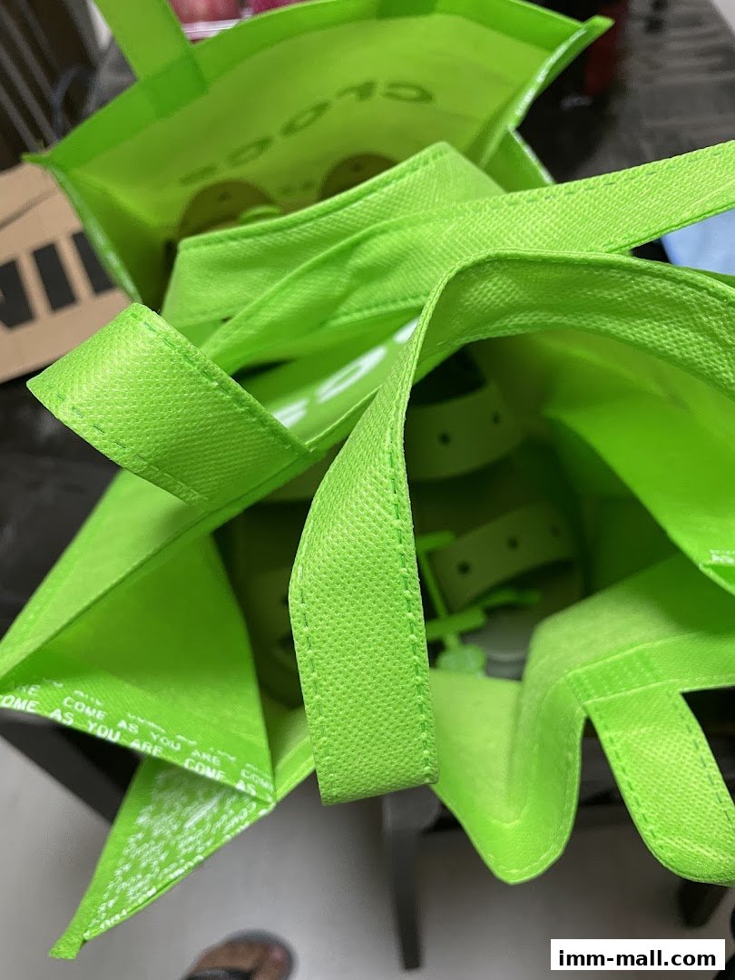 A close-up view inside bright green Crocs shopping bags with visible handles and branding.