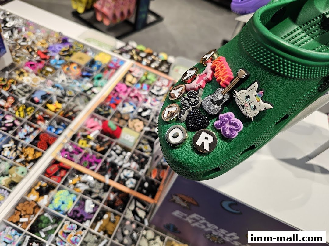 A green Croc shoe adorned with various colorful Jibbitz charms, next to a display of more charms.